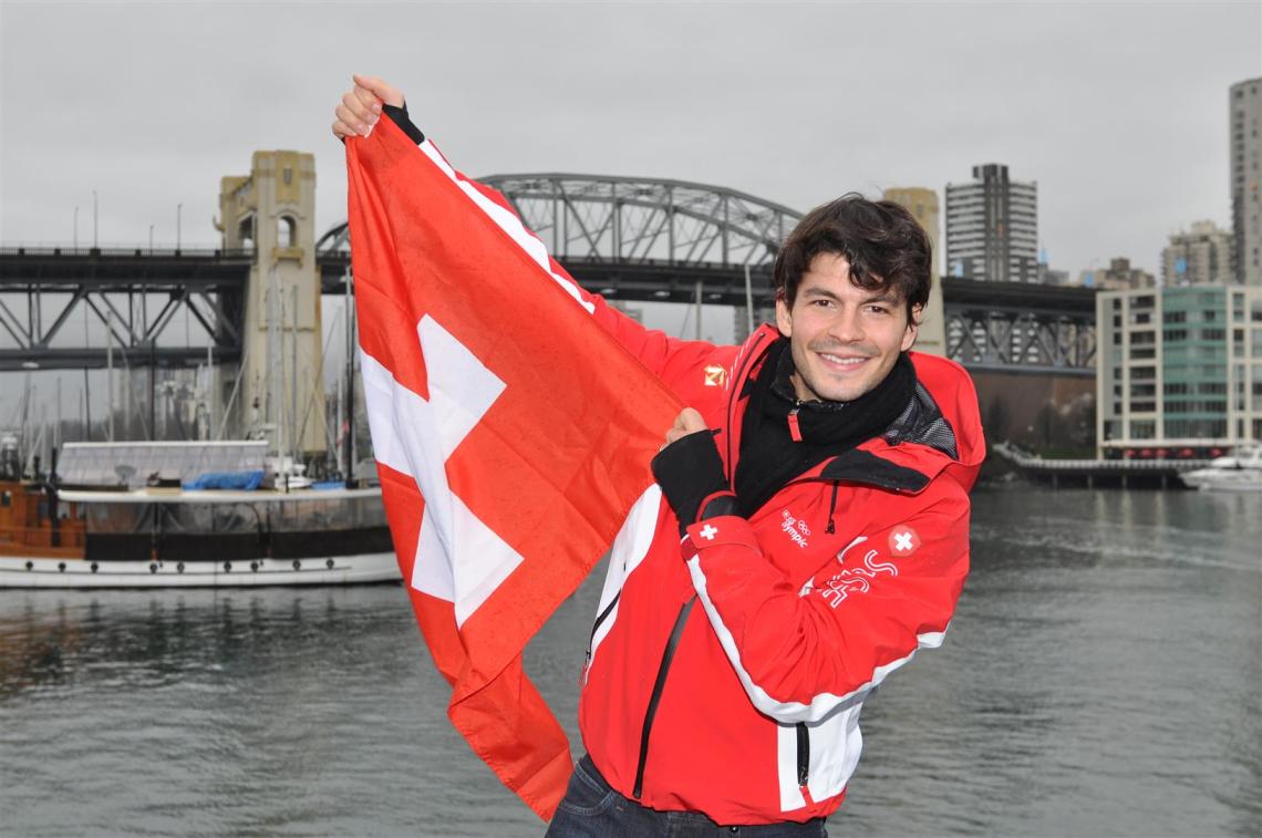 Le patineur suisse Stéphane Lambiel brandit fièrement le drapeau national sur la terrasse de la House of Switzerland, à Vancouver, durant les Jeux olympiques d’hiver 2010 au Canada.