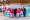 Group photo with a Swiss flag on a wooden terrace in front of a blue mural.