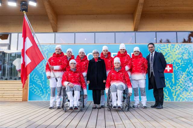 Group photo with a Swiss flag on a wooden terrace in front of a blue mural.