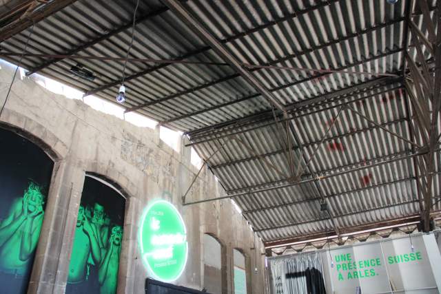 A Swiss presence at the Rencontres d’Arles, set in an industrial exhibition space with bold green visual branding.