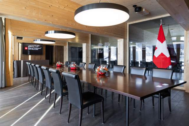 Conference room with a large wooden table and a Swiss flag in the back at the WEF Davos 2025