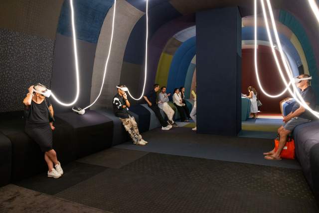 Visitors using virtual reality headsets in a colorful immersive exhibition space.