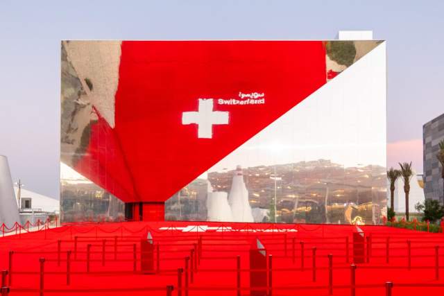 The Swiss Pavilion at Expo 2020 Dubai, featuring its striking mirrored façade, Swiss cross and bold red entrance.