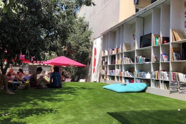 Space outside of the building with grass and people sitting and relaxing on the floor