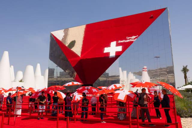 The Swiss Pavilion at Expo 2020 Dubai, with its striking mirrored façade and signature red entrance.