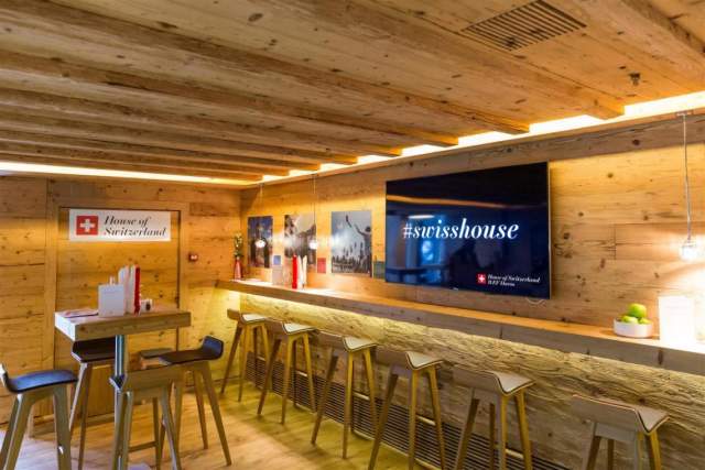 Cosy House of Switzerland lounge in Davos, featuring a warm wooden interior and the #swisshouse display.