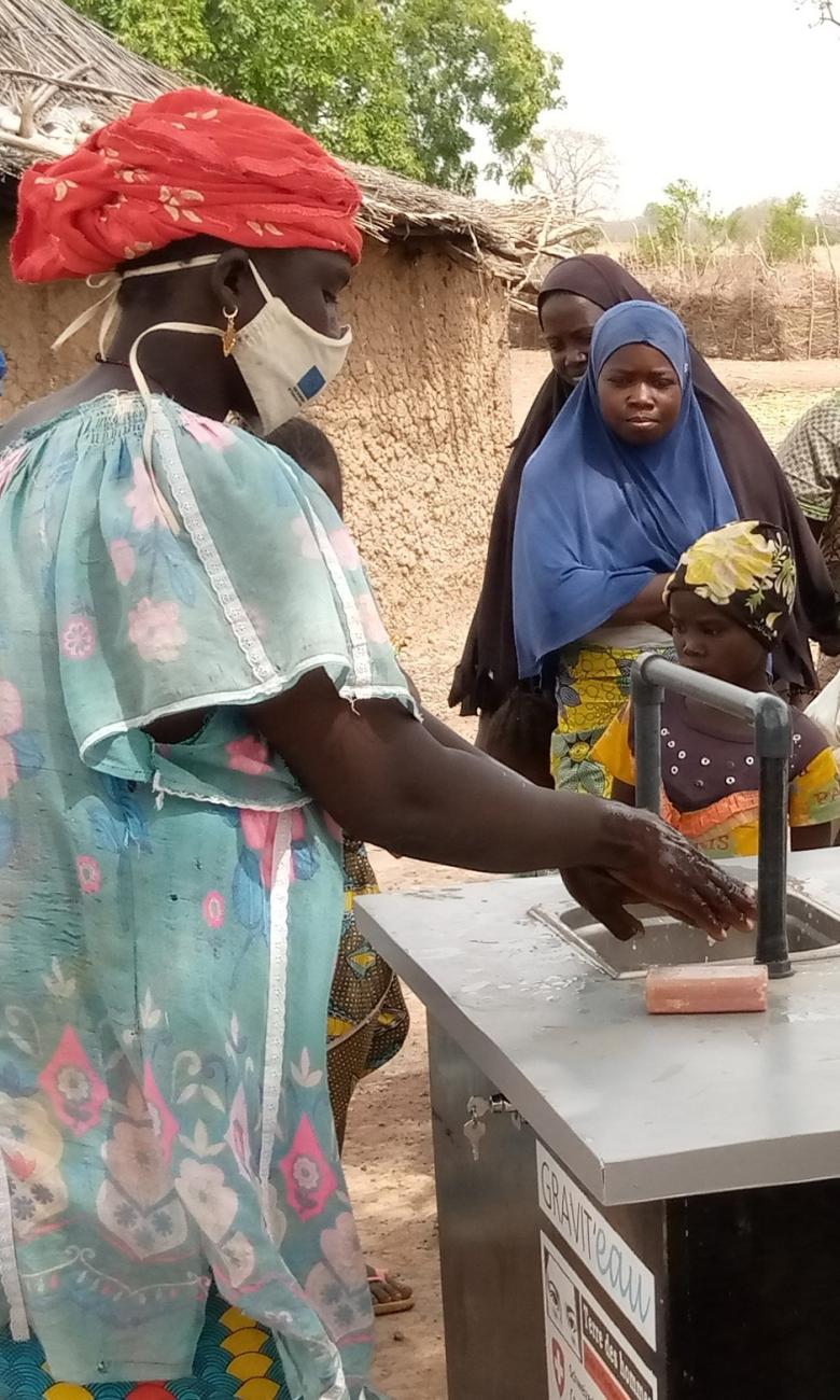 Frauen aus dem Vertriebenenlager Fangasso im Kreis Tominian-Ségou in Mali benutzen 2021 das Wasserrecyclinggerät Gravit'eau, um sich die Hände zu waschen © Terre des hommes